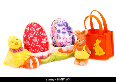 Easter decoration with colorful eggs in ceramic setting, bunny and bag isolated on white background. Stock Photo