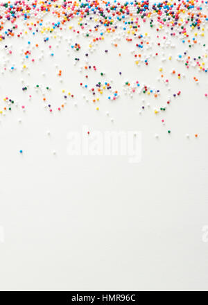 Multi colored nonpareil sprinkles placed as an upper border on a cream paper surface Stock Photo