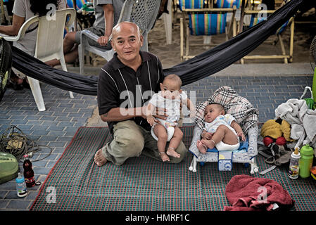 Thailand twins, Thai grandfather with his identical 4 month old twin grandchildren, S.E. Asia Stock Photo
