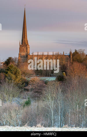 St Marys Church glows in the early morning sunshine as the first light dusting of snow hits the Cotswold town of Tetbury in Gloucestershire. Stock Photo