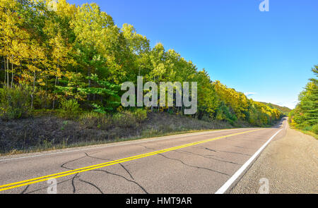 Summer highway open road to anywhere.  Sunny blue sky, woods on either side down a country highway in summertime. Stock Photo