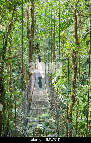 Man standing on hanging bridge in rainforest, La Fortuna, Costa Rica Stock Photo