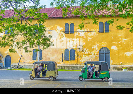 GALLE, SRI LANKA - DECEMBER 3, 2016: The tuk tuks wait the clients at the medieval warehouse building in Queens street of old Fort, on December 3 in G Stock Photo