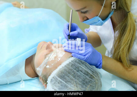 Young blonde woman professional, engaged in reconstruction work responsibly, eyebrows manual method performs procedure, using thinnest needle and mani Stock Photo