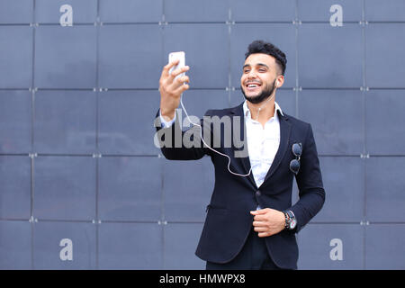 Entrepreneur takes makes selfie man male looking at camera and smiling talks on mobile smart phone. Young handsome businessman arab muslims in busines Stock Photo