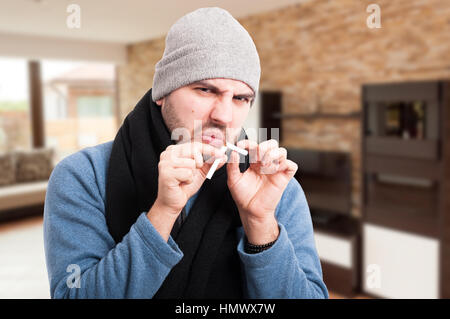 Young man breaking cigarette in two pieces as stop smoking concept Stock Photo