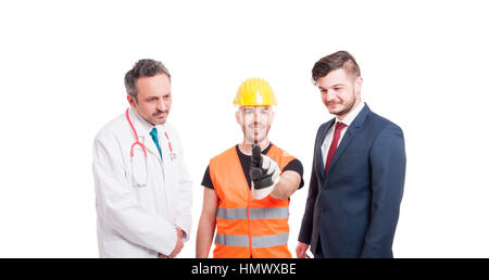Joyful builder pointing on virtual screen while standing near medic and businessman on white background Stock Photo