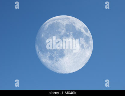 Full moon seen with an astronomical telescope over blue sky Stock Photo