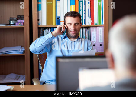Businessman discussing paperwork over the phone in an office Stock Photo