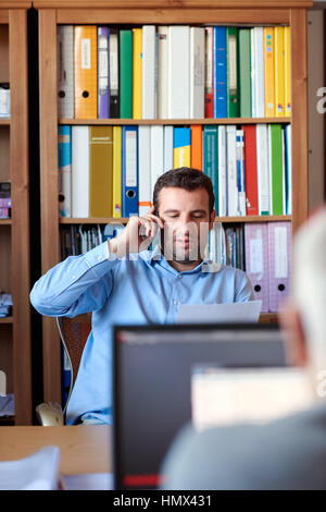 Entrepreneur discussing documents over the phone in an office Stock Photo