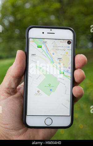 BATH, UK - SEPTEMBER 1, 2015 : Close-up of a male hand holding up a smartphone displaying the Apple map application. Stock Photo