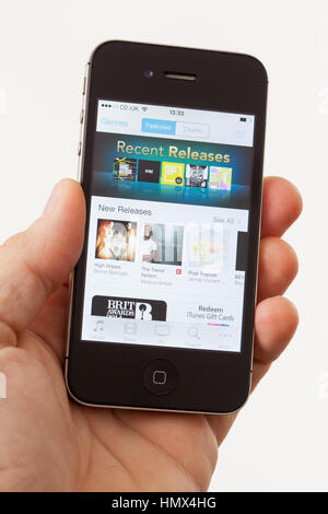 BATH, UK - JANUARY 15, 2014: A man's hand holding an Apple iPhone 4s which is displaying the front page of the Apple iTunes store. Shot in close-up ag Stock Photo