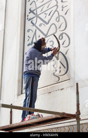 AGRA, INDIA - JANUARY 13, 2015 : A craftsman on a scaffold repairing calligraphic inscriptions in the marble of the north east minaret at the Taj Maha Stock Photo