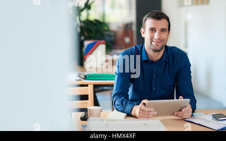 Smiling businessman using a digital tablet in an office Stock Photo