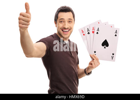 Joyful guy making a thumb up sign and holding four aces isolated on white background Stock Photo