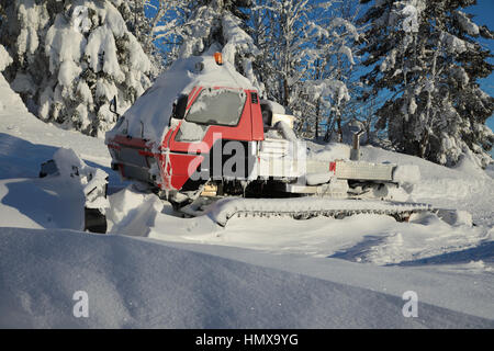 Red snowcat covered in snow on mountains, Red groomer in winter. Stock Photo
