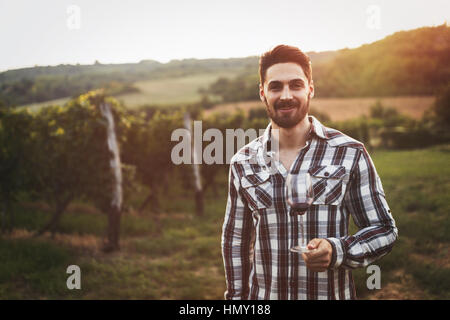 Happy winegrower tasting wine in vineyard in summer Stock Photo