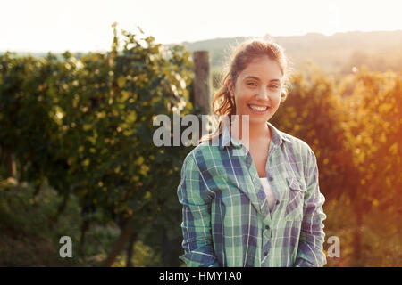 Happy woman in vineyard checking grapes before harvesting Stock Photo