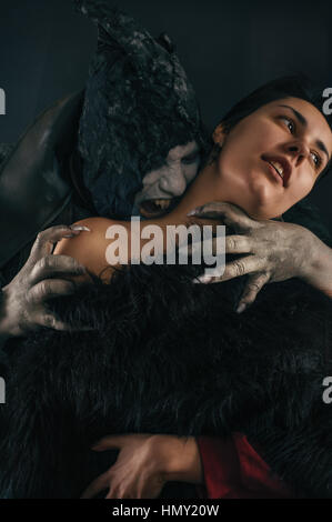 Scary vampire devil biting young woman. Medieval gothic nightmare horror. Studio shoot Stock Photo