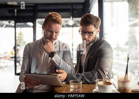 Smart businessman wearing suit using tablet in cafe Stock Photo