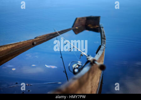 Fishing rod on the background of the submerged boat in the waters of the river fall. Stock Photo