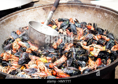 Cooking crayfish and mussels on a fire in a large saucepan. Stock Photo