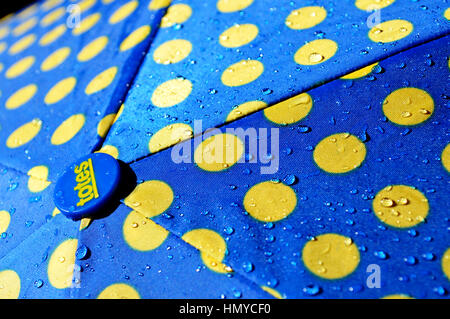 Rain drops on a blue and yellow umbrella. Stock Photo
