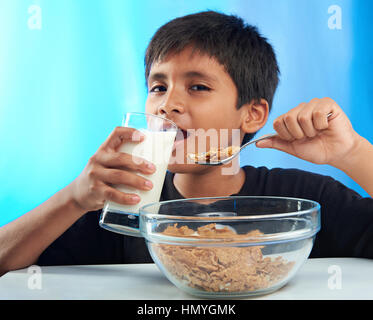 hispanic boy eating breakfast isolated on blue Stock Photo