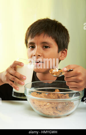 boy eating cereal and milk isolated on yellow background Stock Photo