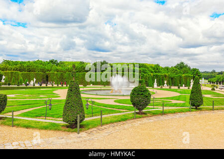VERSAILLES,  FRANCE- JULY 02, 2016 : Fountain near the flower bed in a Famous Gardens of Versailles (Chateau de Versailles). Stock Photo