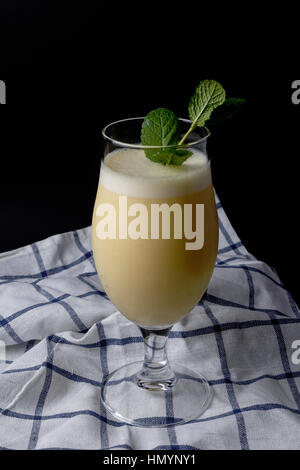 Cocktail of pineapple colada with mint on a cloth and the black background Stock Photo