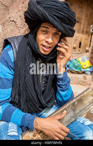 Morocco.  Teenage Amazigh Berber Young Man Talking on his Cell Phone, Ait Benhaddou Ksar, a World Heritage Site. Stock Photo