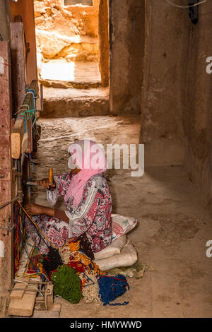 Morocco.  Berber Woman Weaving a Rug in her Home.  Ait Benhaddou Ksar, a World Heritage Site. Stock Photo