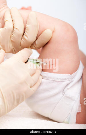 Close-up shot of pediatrician giving a three month baby girl  intramuscular injection in leg Stock Photo