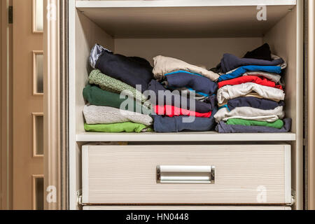 A stack of knitted warm woolen clothes in wardrobe close up Stock Photo