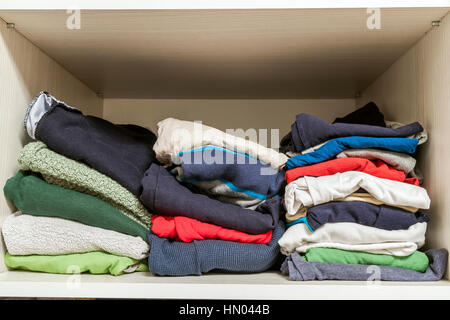 A stack of knitted warm woolen clothes in wardrobe close up Stock Photo