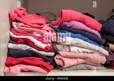 A stack of knitted warm woolen clothes in wardrobe close up Stock Photo