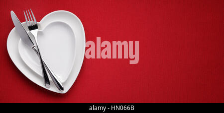 plate in shape of heart, table knife and fork on red Stock Photo