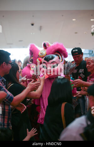 Lion dance and big head buddha blessing the crowd as they arrive at Pavillion shopping mall, Kuala Lumpur Malaysia. Stock Photo
