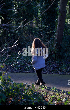 Young female walking away through a park. Rear view. Stock Photo