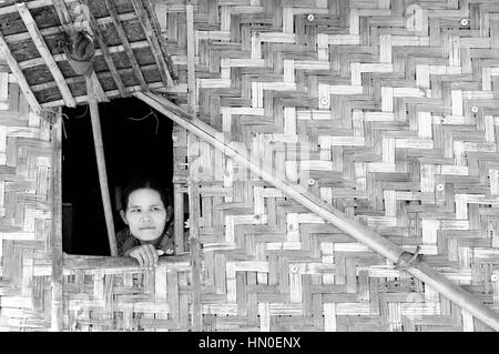 INLE LAKE, MYANMAR - JANUARY 12: Portrait of the Burmese woman in traditional make-up looking through the window from the traditional Burmese cottage  Stock Photo