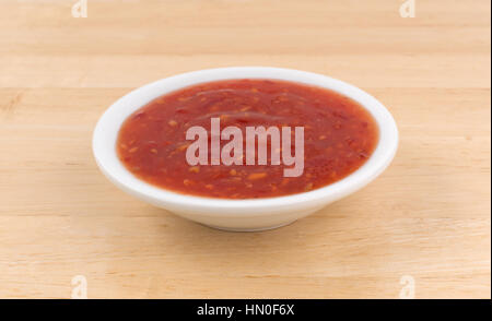 Chili chicken hot sauce in a small bowl on a wood table. Stock Photo