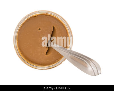 Top view of an opened jar of cookie butter with a spoon inserted into the food isolated on a white background. Stock Photo