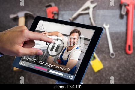 Man using tablet pc  against portrait of handyman fixing washing machine Stock Photo