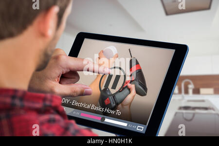 Man using tablet table against handyman installing smoke detector with power drill Stock Photo