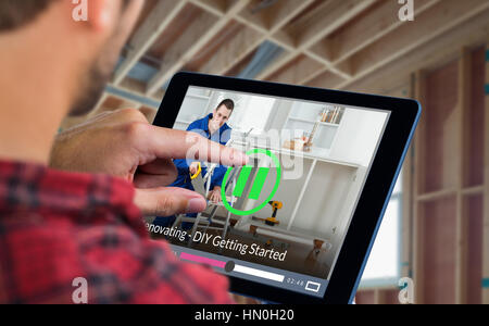 Man using tablet on wooden table against smiling handyman cutting wooden board Stock Photo