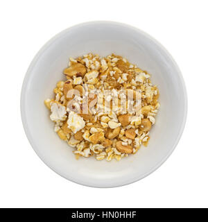 Top view of a bowl with toffee caramel popcorn crumbs with nuts at the bottom isolated on a white background. Stock Photo