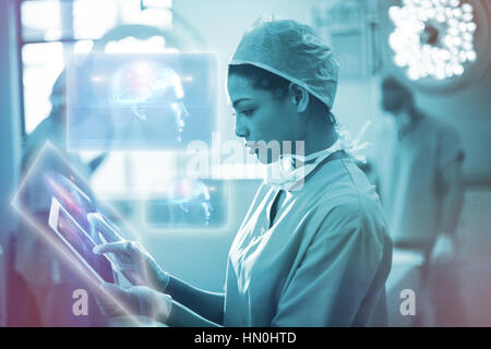 Brain diagram in human head against female surgeon using digital tablet in operation room 3d Stock Photo