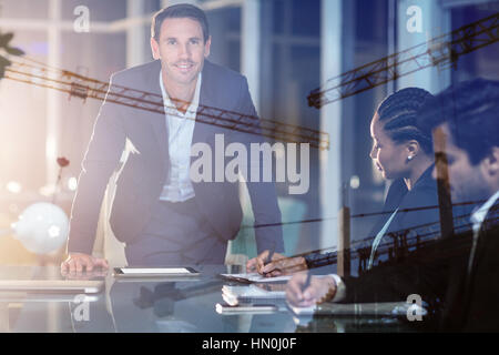 Crane and building construction site against businessman with coworkers in meeting Stock Photo