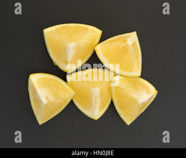 Top view of several white grapefruit chunks on a black slate cutting board. Stock Photo